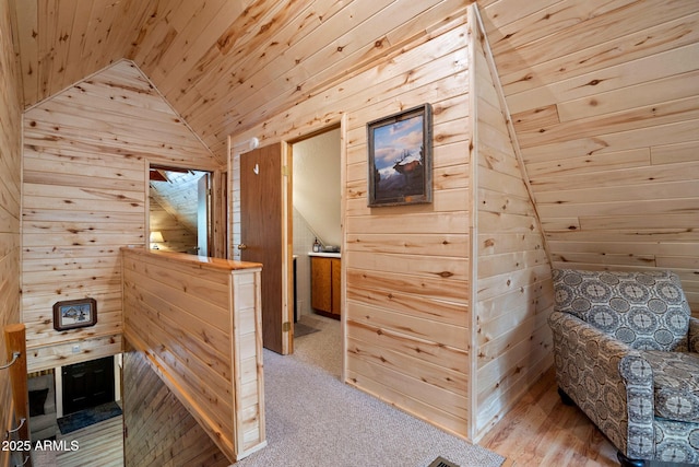 interior space featuring wooden ceiling, lofted ceiling, wooden walls, and carpet floors