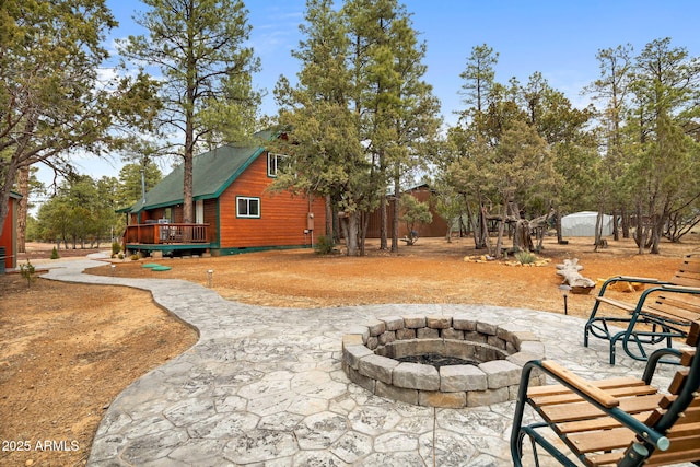 exterior space with an outdoor fire pit, a wooden deck, and an outbuilding