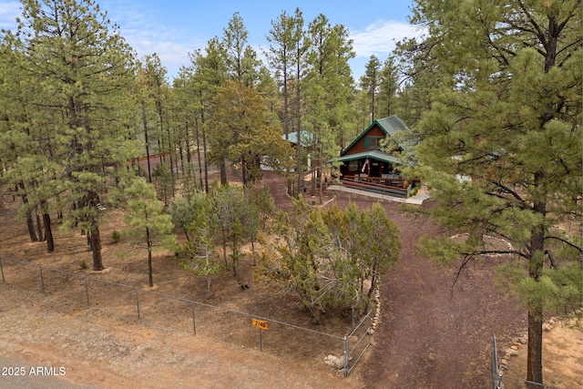 view of yard featuring a wooded view and fence