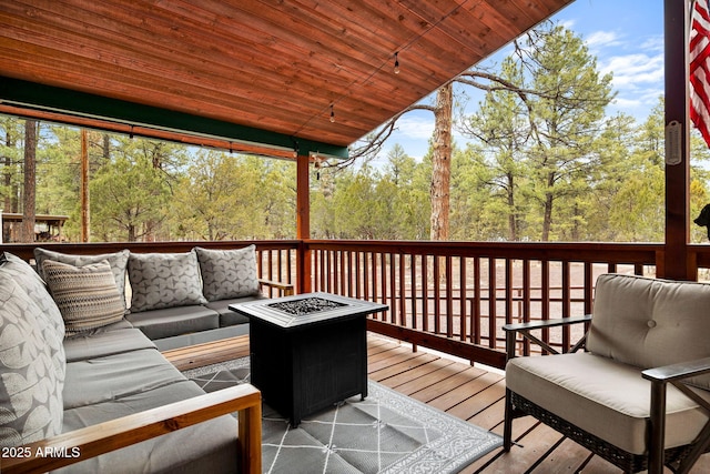 deck with a view of trees and an outdoor living space with a fire pit
