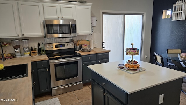 10036 W Chipman Rd, Tolleson, AZ 85353 - kitchen with appliances with stainless steel finishes, white cabinetry, backsplash, light tile patterned floors, and a kitchen island