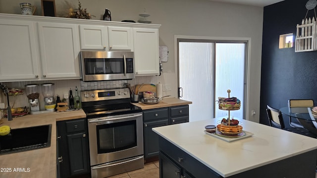10036 W Chipman Rd, Tolleson, AZ 85353 - kitchen with stainless steel appliances, white cabinets, decorative backsplash, light tile patterned floors, and a kitchen island