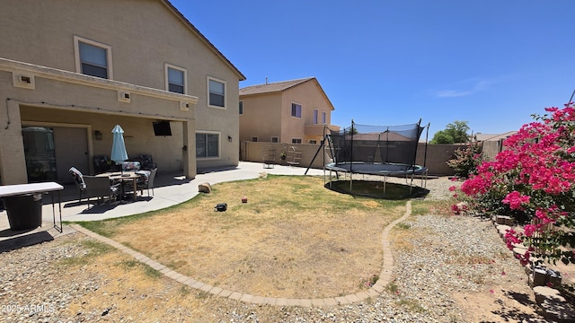 10036 W Chipman Rd, Tolleson, AZ 85353 - back of property featuring a trampoline, stucco siding, a patio, and a fenced backyard