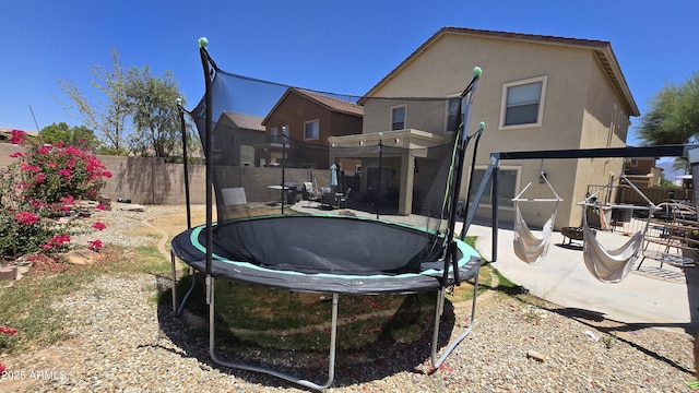 10036 W Chipman Rd, Tolleson, AZ 85353 - rear view of house with a trampoline, stucco siding, and a patio area