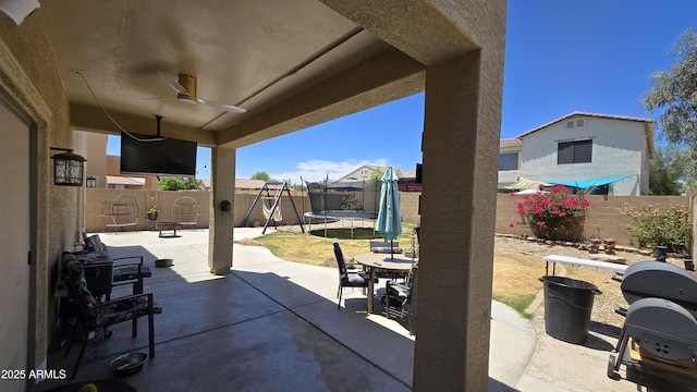 10036 W Chipman Rd, Tolleson, AZ 85353 - fenced backyard with a trampoline, a patio area, ceiling fan, a grill, and outdoor dining area