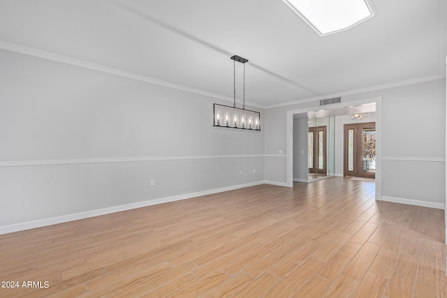 empty room featuring french doors, crown molding, and light wood-type flooring