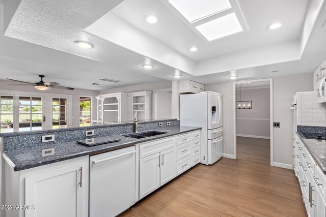 kitchen with backsplash, white appliances, ceiling fan, dark stone counters, and light wood-type flooring