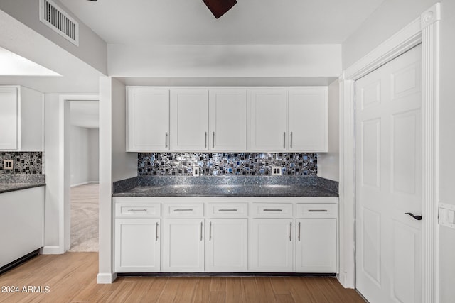 kitchen with backsplash, light colored carpet, and white cabinets