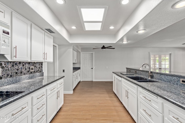 kitchen featuring ceiling fan, tasteful backsplash, white cabinets, sink, and light wood-type flooring