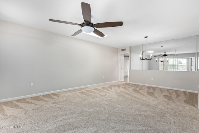 carpeted spare room with ceiling fan with notable chandelier