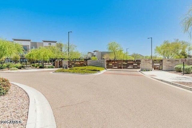 6503 E Bluefield Ave, Phoenix, AZ 85054 - view of asphalt road with sidewalks, a gate, curbs, street lights, and a gated entry