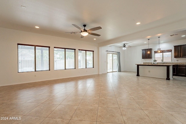 unfurnished living room featuring ceiling fan, light tile patterned floors, and sink