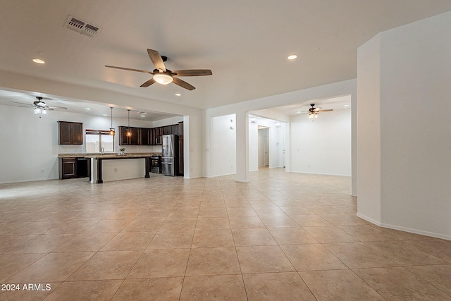 unfurnished living room with sink, light tile patterned floors, and ceiling fan