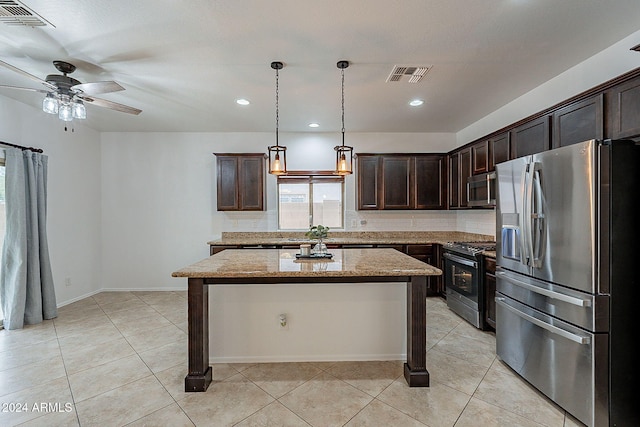 kitchen with light stone counters, dark brown cabinets, a kitchen island, pendant lighting, and appliances with stainless steel finishes