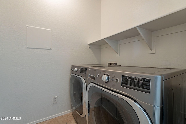 laundry area with washer and clothes dryer and light tile patterned floors