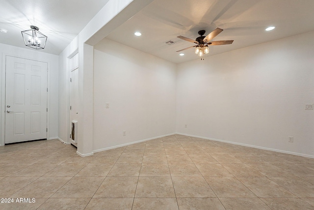 spare room featuring ceiling fan with notable chandelier and light tile patterned floors