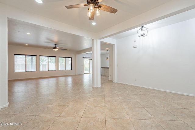 unfurnished room featuring ceiling fan with notable chandelier and light tile patterned floors