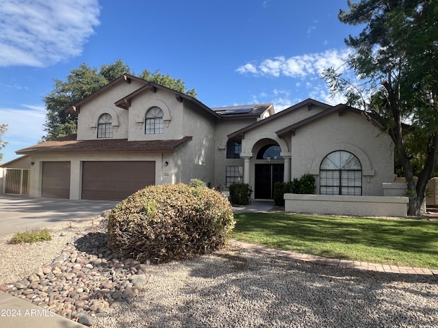 view of front of home featuring driveway, an attached garage, roof mounted solar panels, a front lawn, and stucco siding