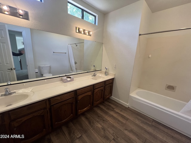 full bath with a sink, shower / bathtub combination with curtain, toilet, and wood finished floors