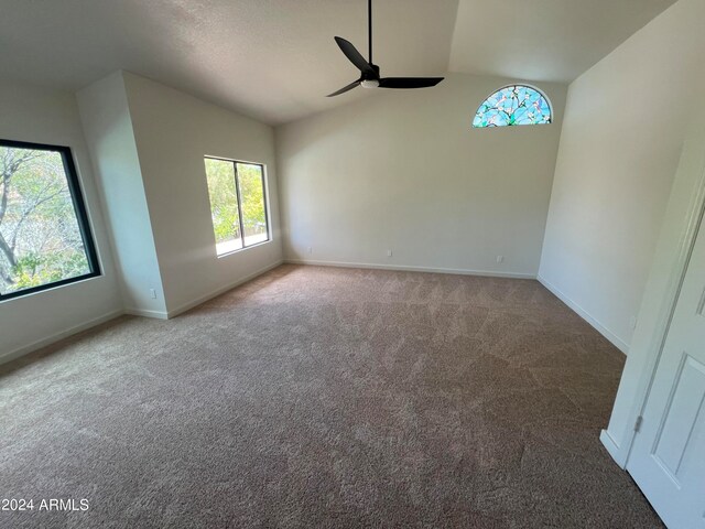 carpeted spare room with ceiling fan and vaulted ceiling