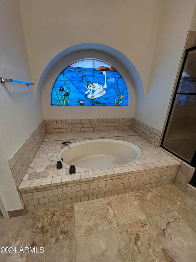 interior space with tiled tub and tile patterned floors