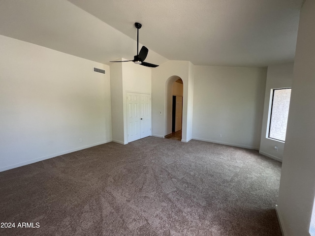 carpeted spare room featuring ceiling fan, arched walkways, visible vents, baseboards, and vaulted ceiling