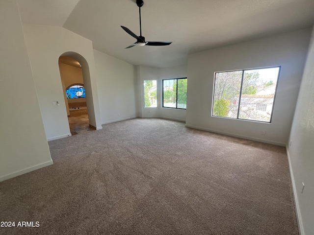 carpeted spare room with a ceiling fan, arched walkways, lofted ceiling, and baseboards