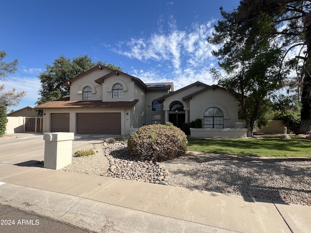 mediterranean / spanish-style home featuring driveway, a garage, solar panels, fence, and stucco siding