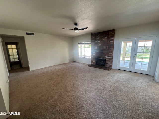 unfurnished living room with a fireplace, a textured ceiling, carpet floors, and brick wall