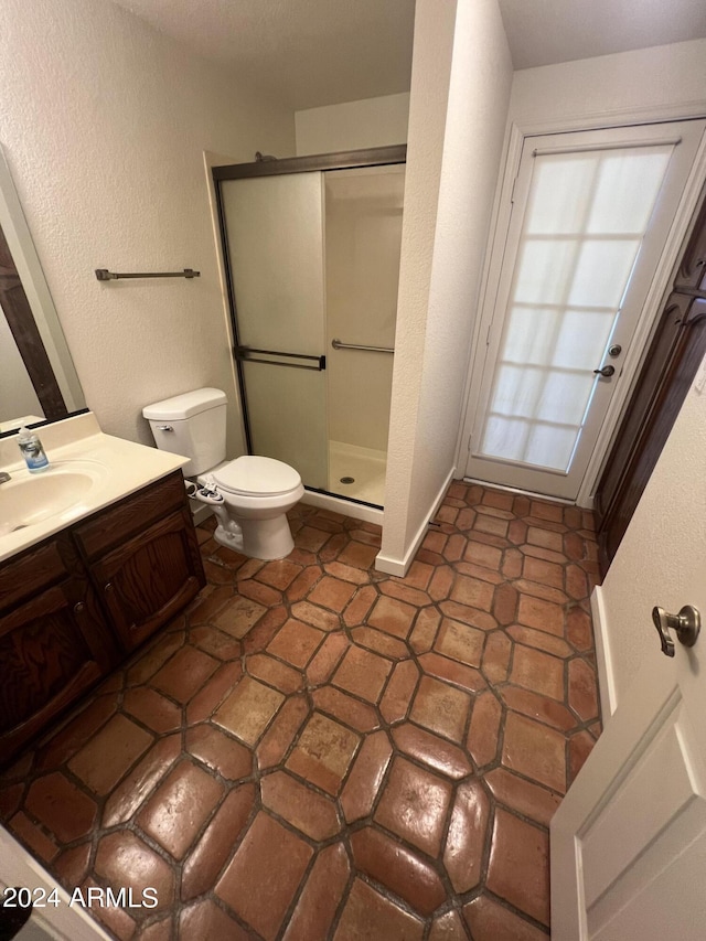 bathroom featuring toilet, a shower stall, vanity, and a textured wall