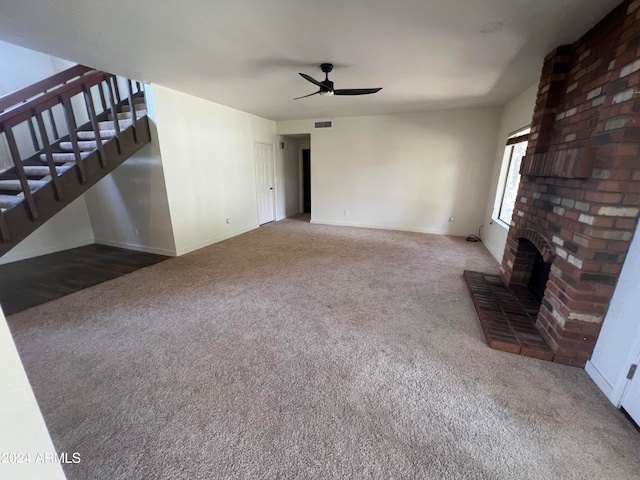 living room featuring ceiling fan, a fireplace, carpet flooring, and brick wall