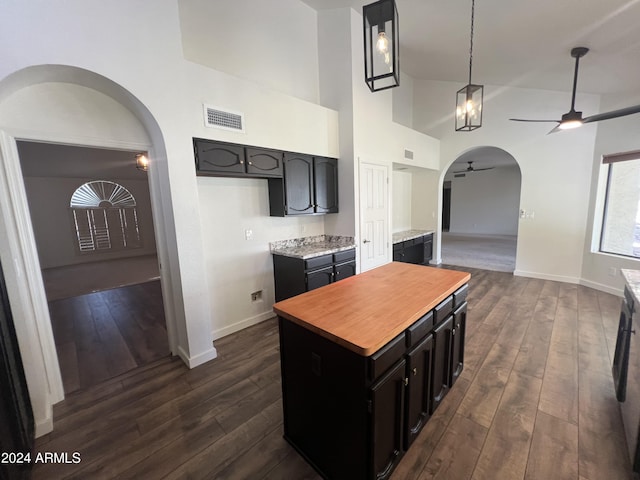 kitchen featuring visible vents, arched walkways, dark wood finished floors, ceiling fan, and a kitchen island