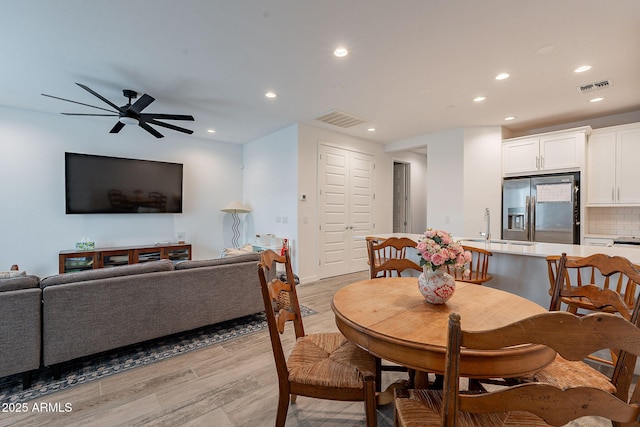 dining space featuring ceiling fan, sink, and light hardwood / wood-style floors