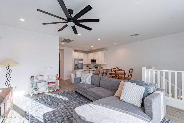 living room with ceiling fan and light hardwood / wood-style floors