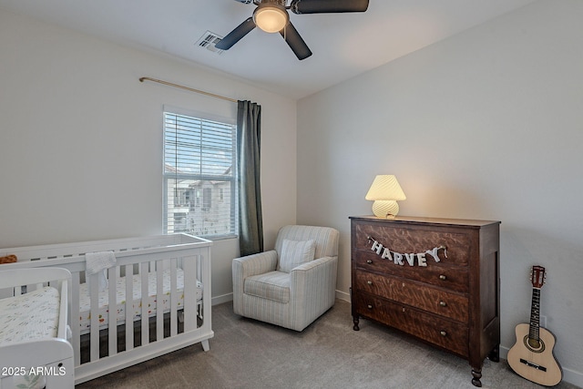 bedroom with ceiling fan, light colored carpet, and a nursery area