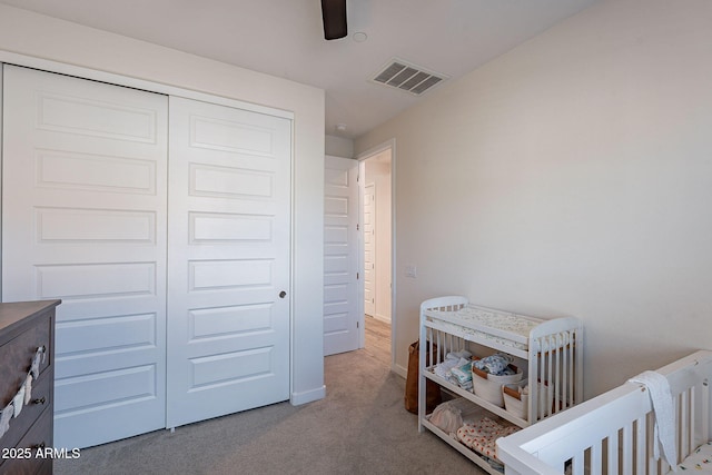 bedroom featuring ceiling fan, light colored carpet, and a closet