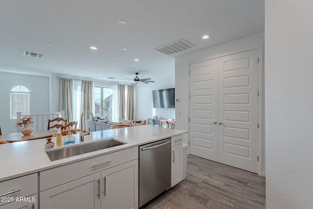 kitchen with ceiling fan, light wood-type flooring, stainless steel dishwasher, white cabinets, and sink