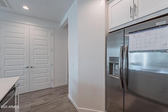 kitchen featuring light wood-type flooring, appliances with stainless steel finishes, and white cabinetry