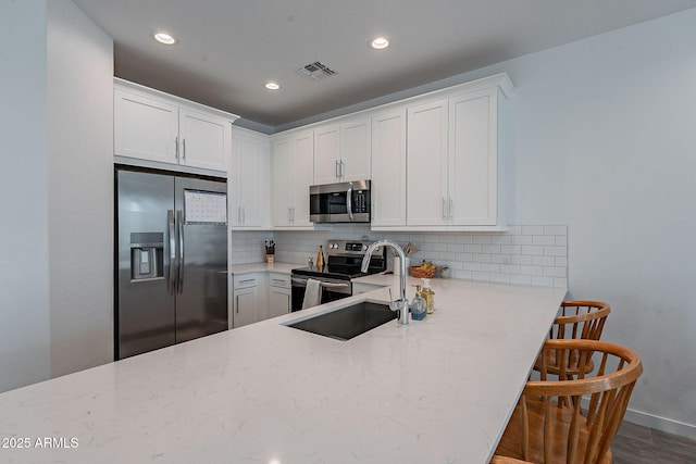 kitchen with white cabinets, backsplash, and appliances with stainless steel finishes