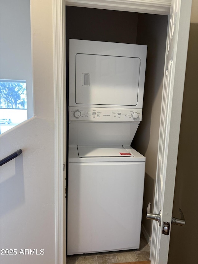 washroom featuring stacked washer / drying machine and light tile patterned floors