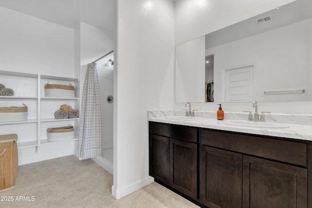 bathroom featuring a shower with shower curtain, double vanity, tile patterned flooring, and baseboards