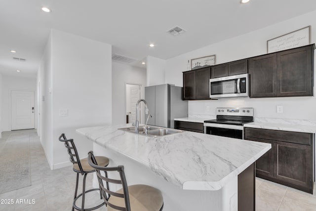 kitchen featuring appliances with stainless steel finishes, a center island with sink, a sink, light tile patterned floors, and recessed lighting