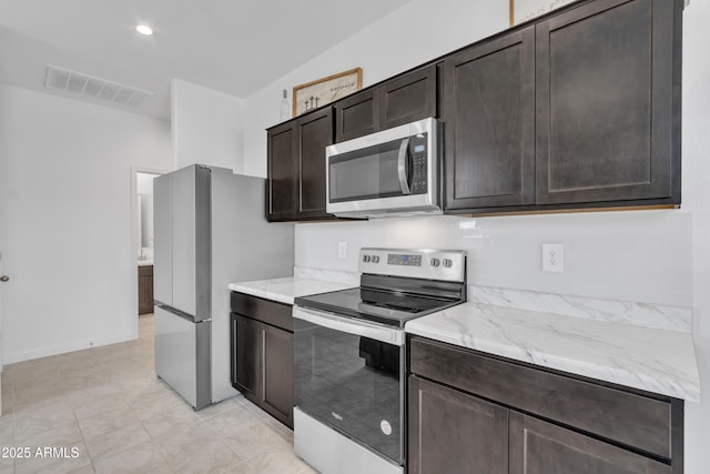 kitchen featuring stainless steel appliances, dark brown cabinets, and light stone countertops