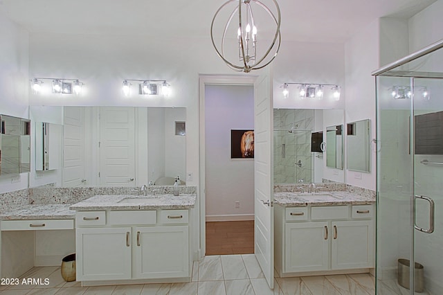 bathroom featuring large vanity, a shower with shower door, dual sinks, tile flooring, and an inviting chandelier