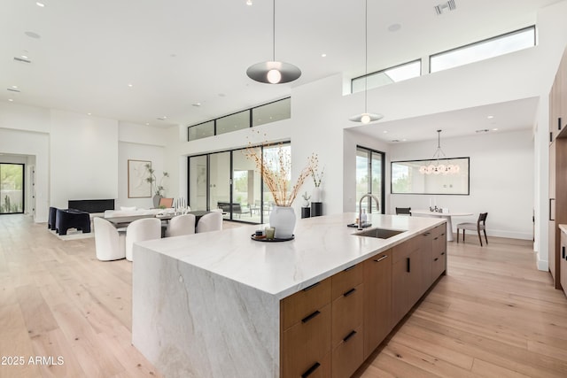 kitchen featuring a large island with sink, modern cabinets, light wood finished floors, and a sink