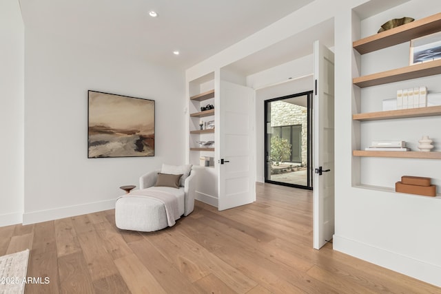 sitting room featuring built in features, recessed lighting, baseboards, and light wood-style floors