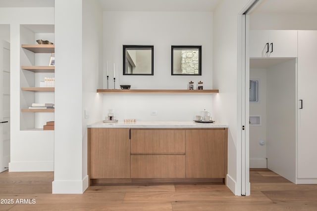 bar with built in shelves, light wood-style floors, and baseboards