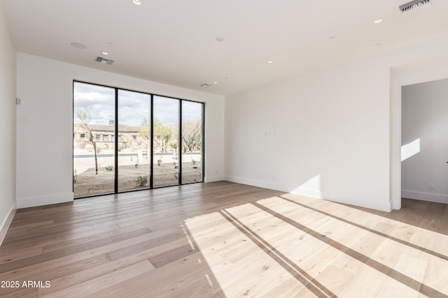 empty room featuring recessed lighting, visible vents, light wood-style flooring, and baseboards