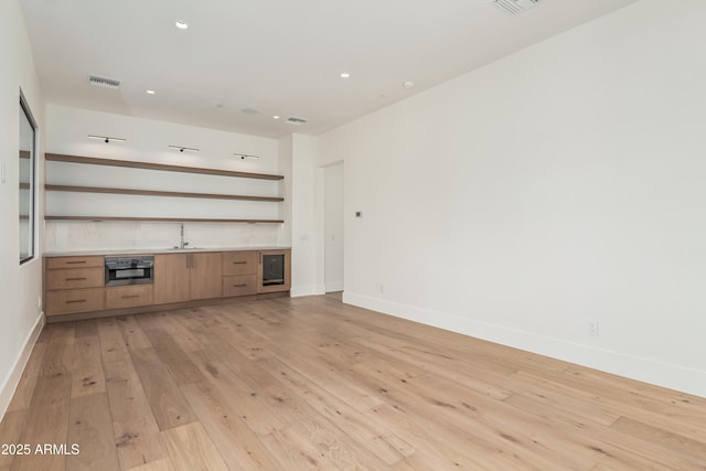 unfurnished living room featuring light wood finished floors, visible vents, recessed lighting, and baseboards