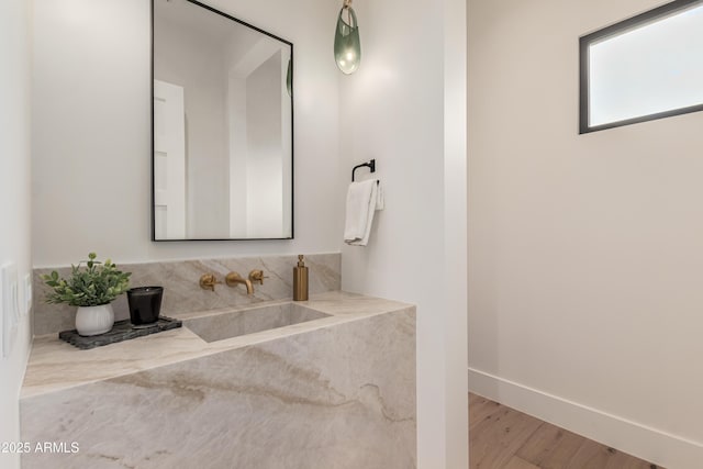 bathroom with wood finished floors, baseboards, and a sink